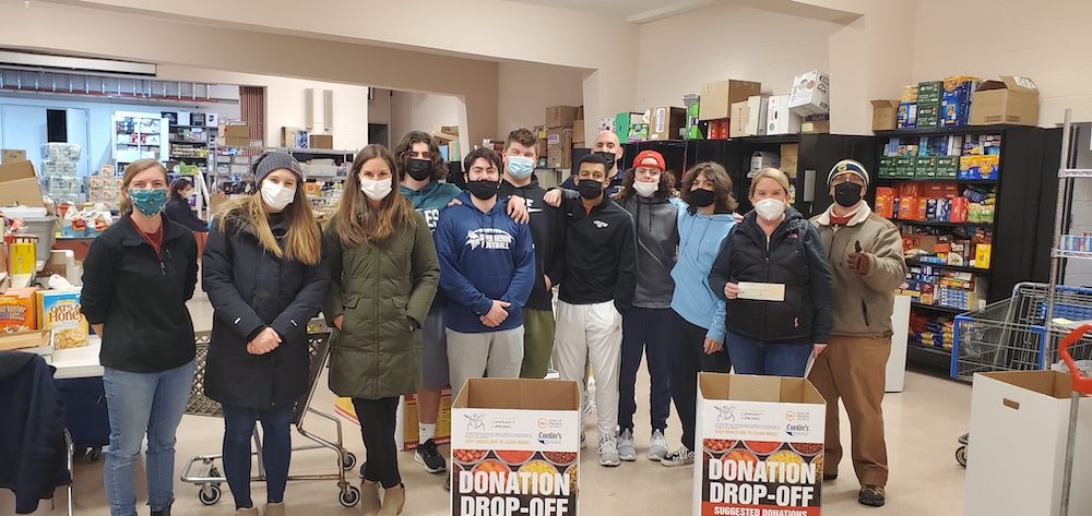 group of people wearing masks standing together in a food pantry