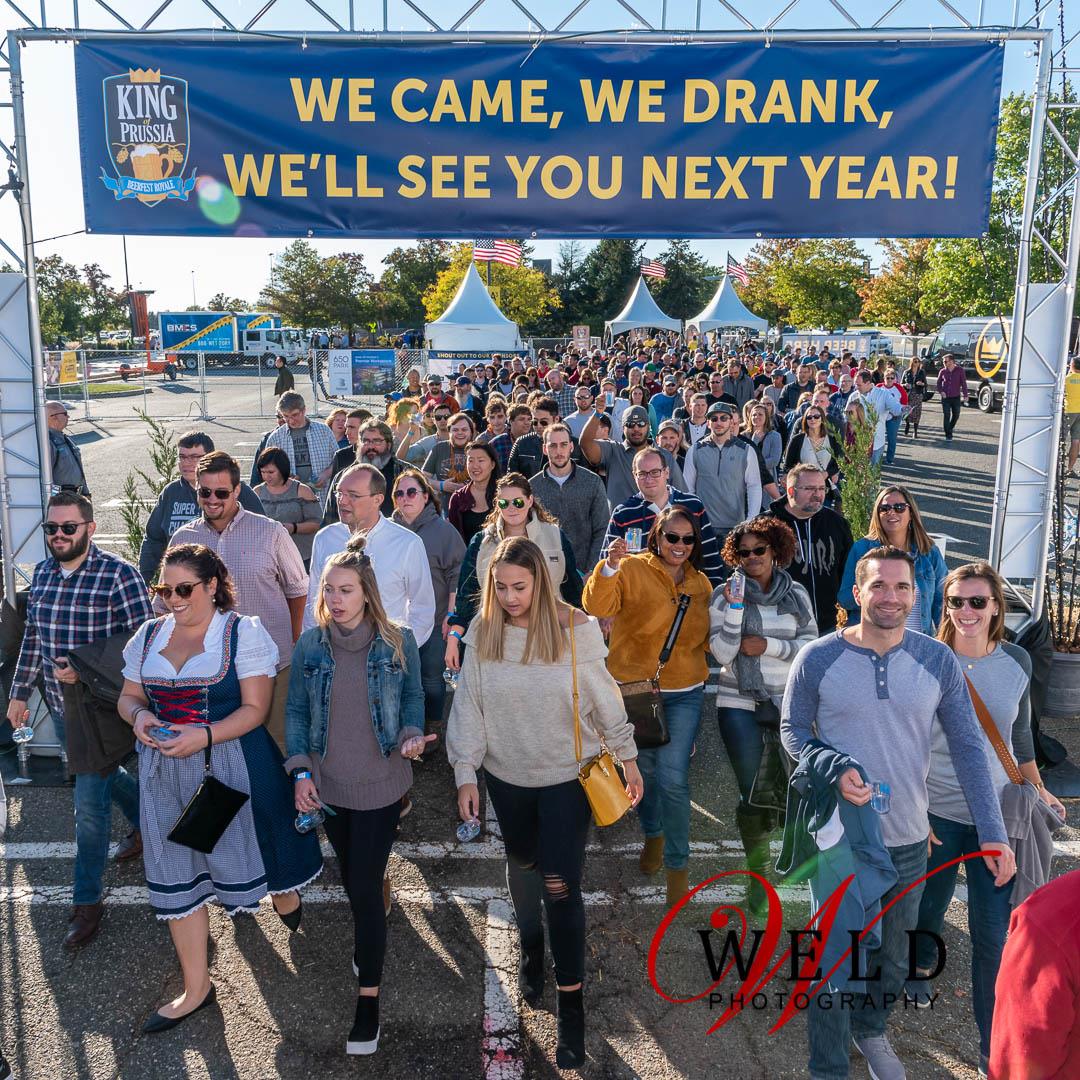 crowd walking under a large sign