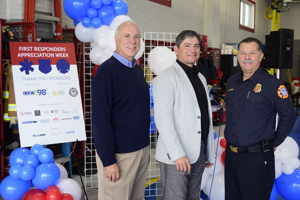 three people standing in front of red, white and blue balloons smiling