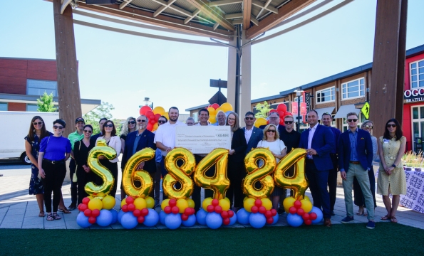 group of people standing behind giant balloon numberes reading "$68,484"