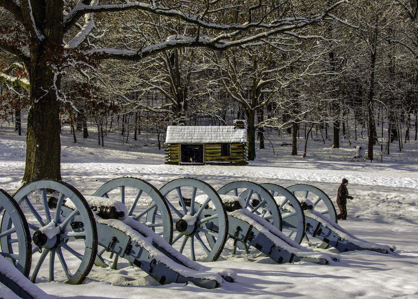Winter outdoor scene with historical canons and a wood cabin in the snow