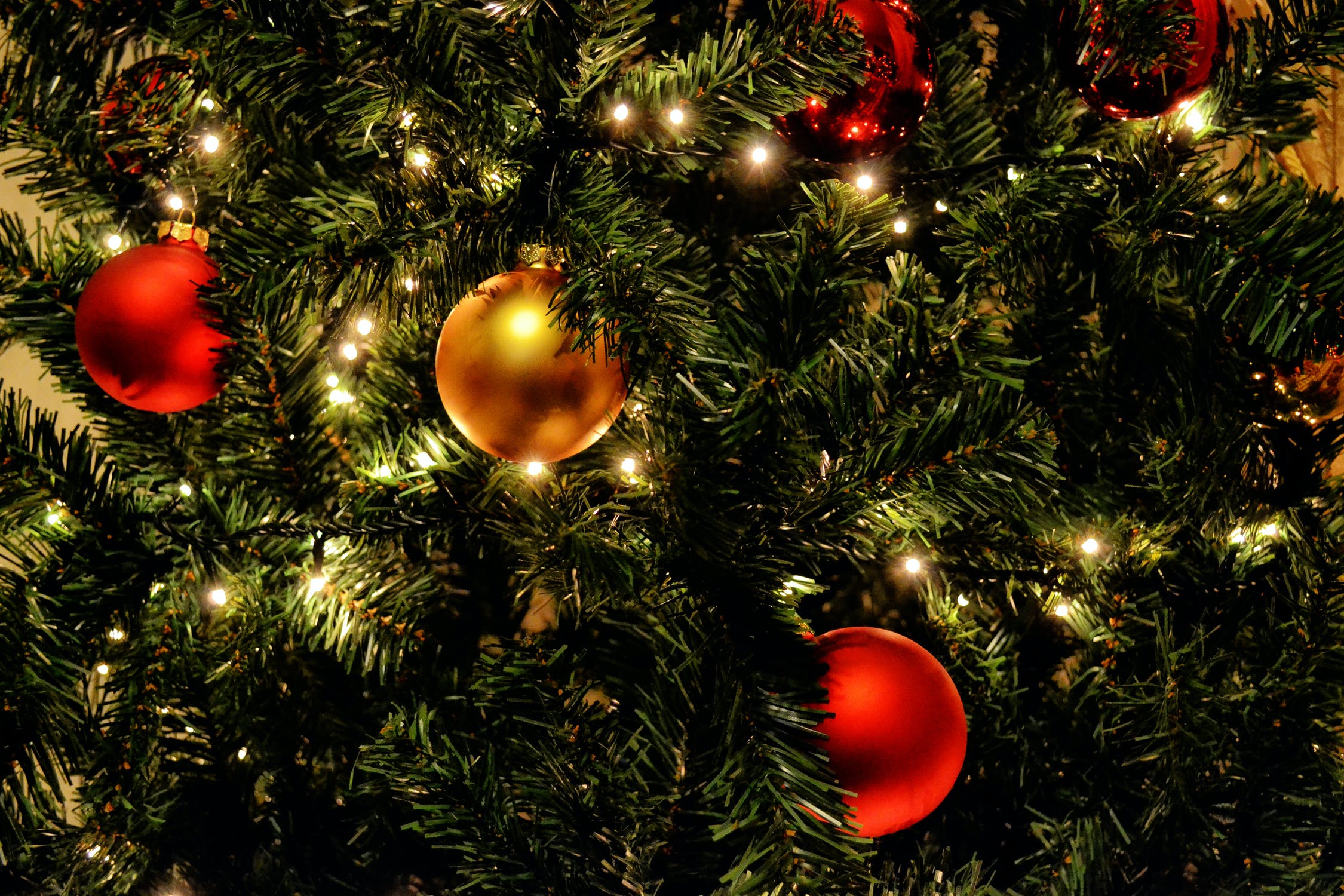 close up image of pine tree with colorful round ornaments and lights