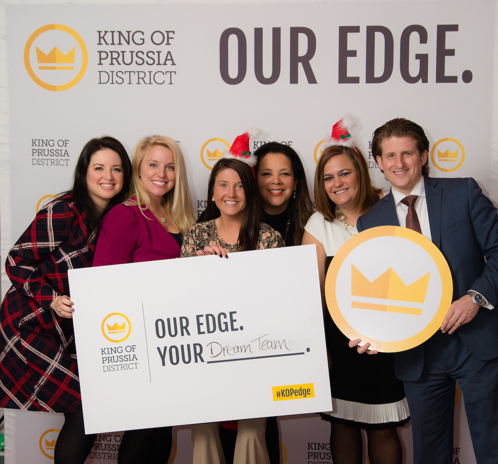 A group of people holding signs and posing in front of a step n repeat