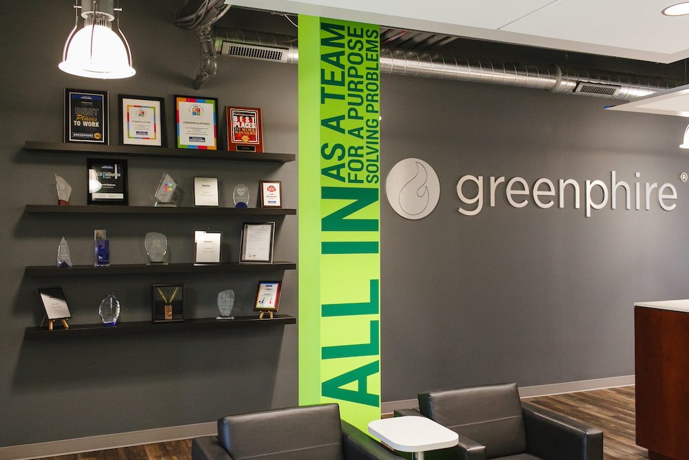 chairs in front of a grey wall with bright green detail, shelving and awards