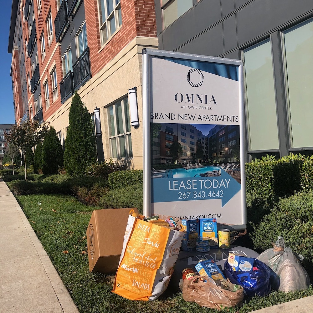 Omnia town center sign outdoors, surrounded by bags of non-perishable food items