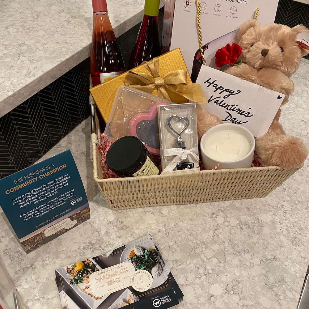 a gift basket with wine bottles, a teddy bear and other various items