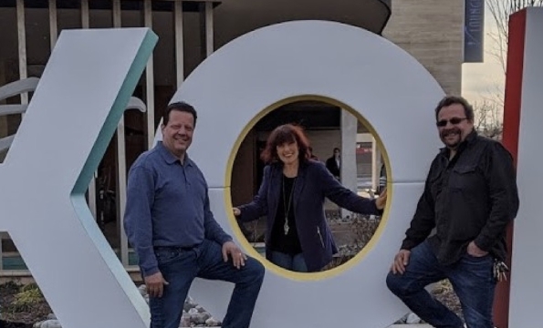 Three people standing outdoors around large letters