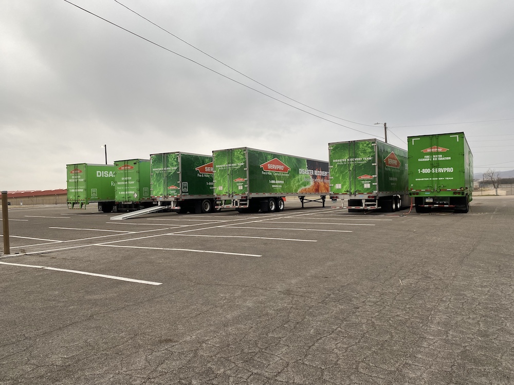 a line of green box trucks in a parking lot