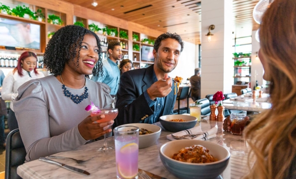 woman and man eating pasta and talking to person across table