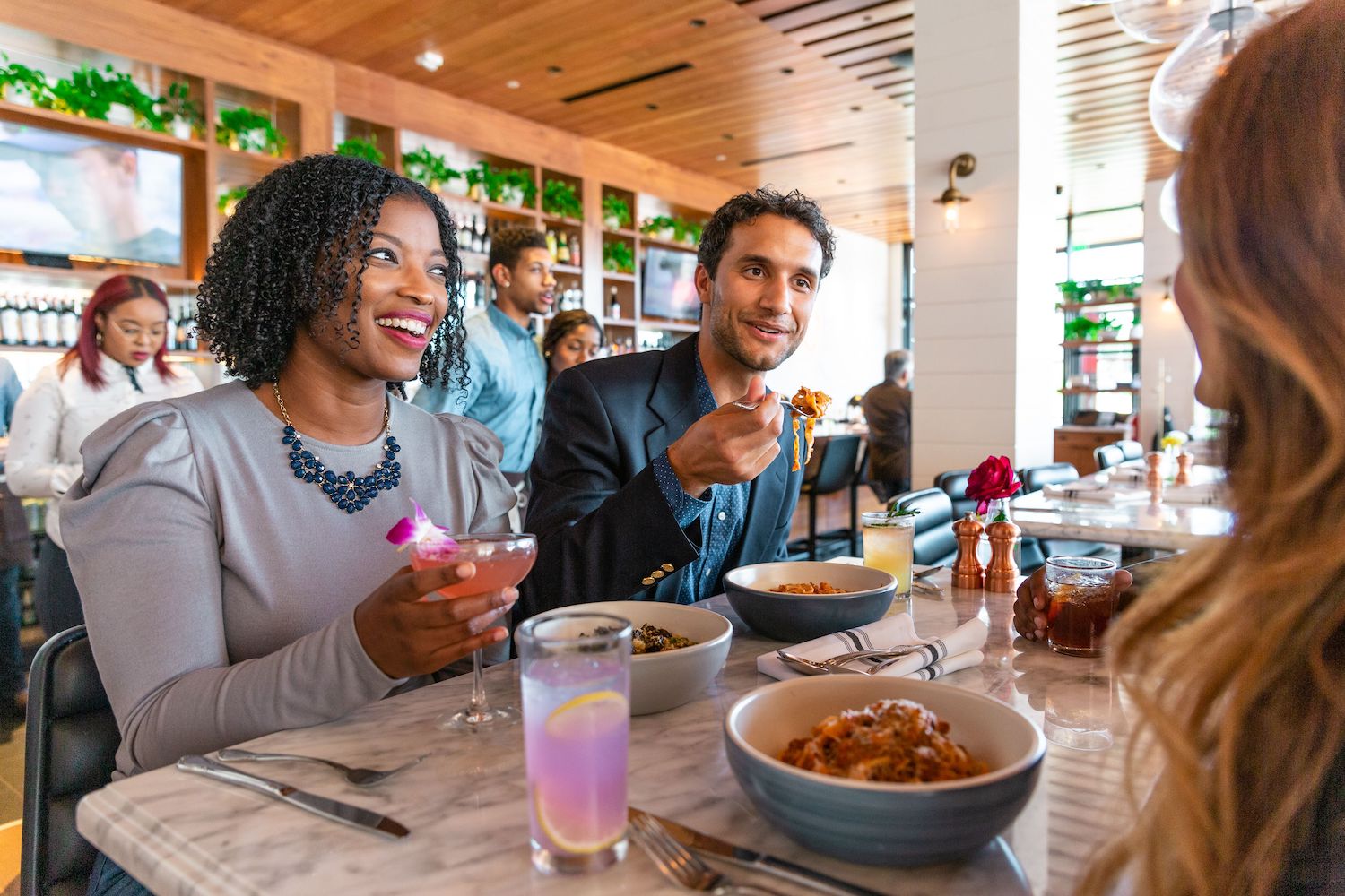 woman and man eating pasta and talking to person across table