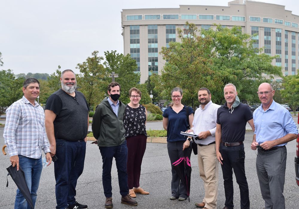 group of people standing outdoors smiling at the camera with large building in the background