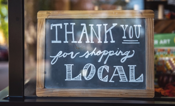 chalkboard sign in a window that says "Thank you for shopping local"