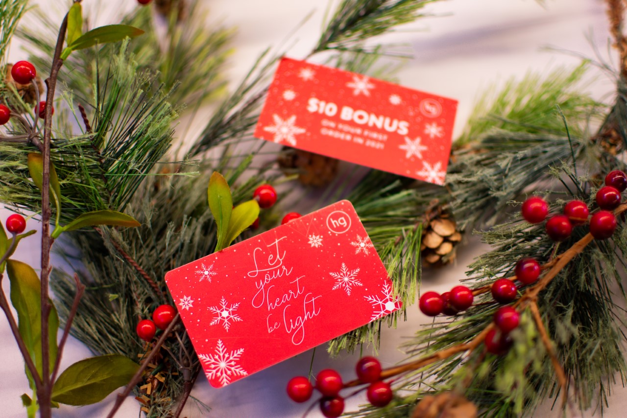 gift cards sitting on top of pine needles and berries