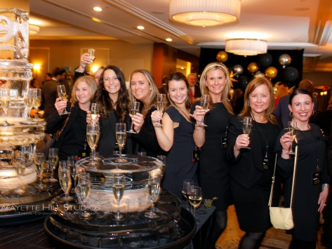 group of people standing beside an ice sculpture holding champagne glasses