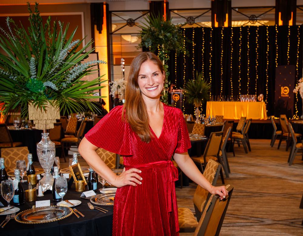 person in red dress smiling in a large empty ballroom