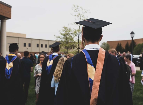 college graduates walking in robes and caps