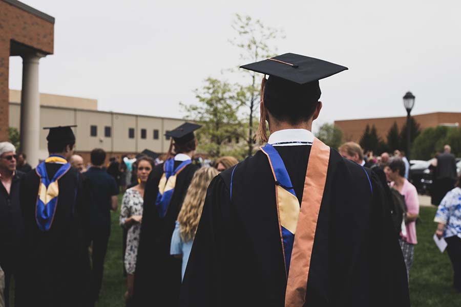 college graduates walking in robes and caps