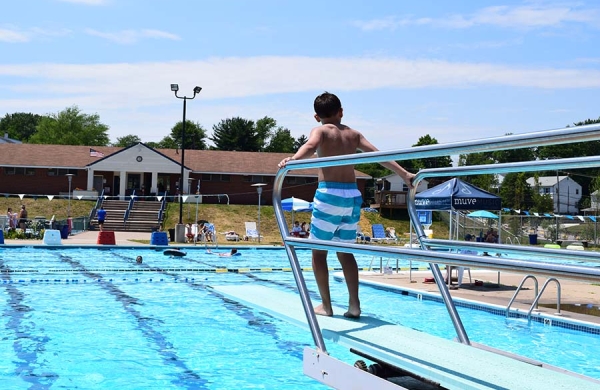 child on diving board at pool