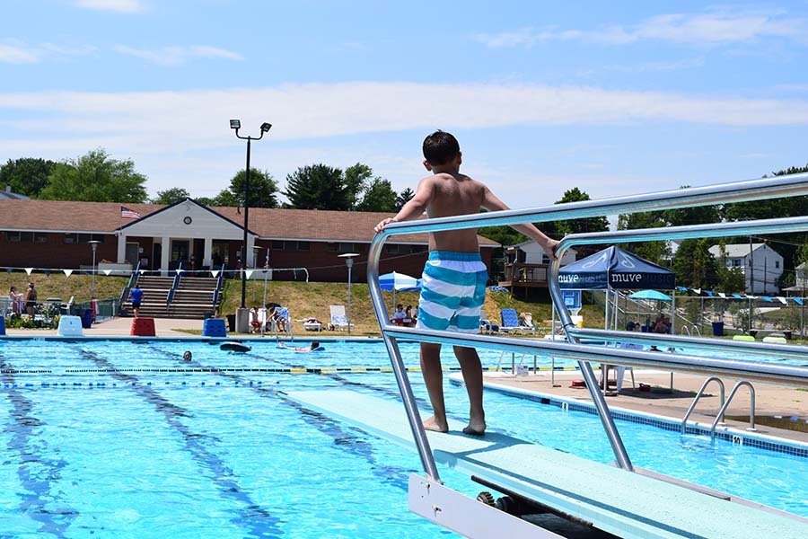 child on diving board at pool
