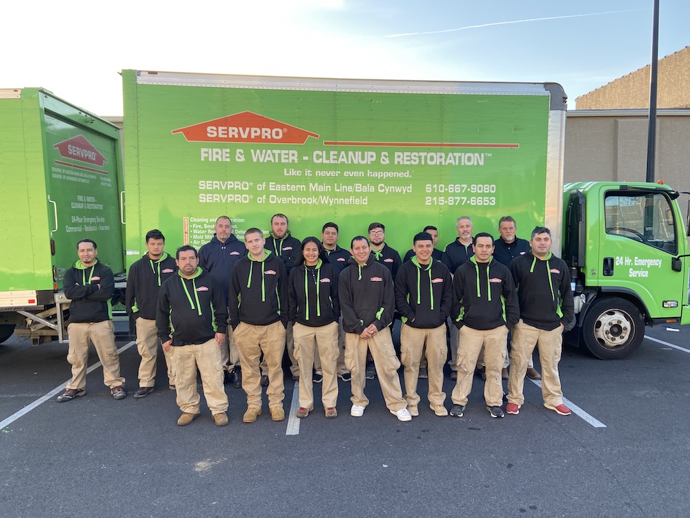 group of people in uniform standing in front of a green SERVPRO truck