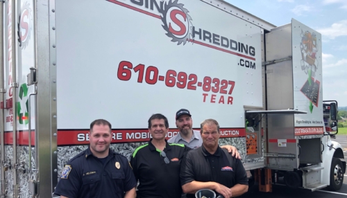 four people smiling in front of a truck