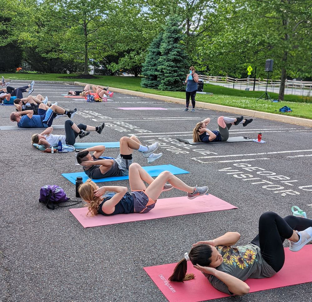 Group of people exercising on yoga mats in a parking lot