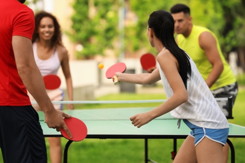 four people playing ping pong outdoors