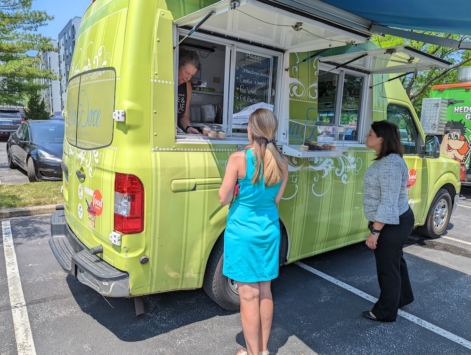two people standing outdoors by a green food truck