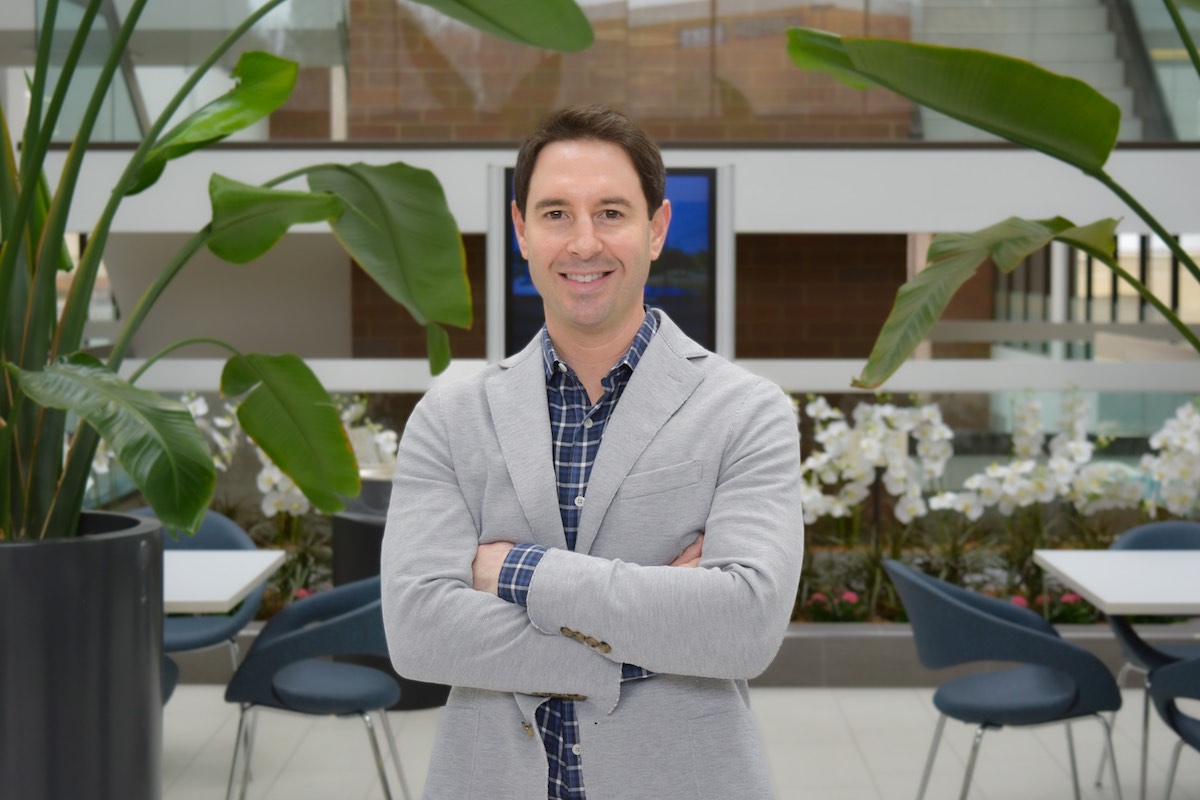 man smiling in front of foliage