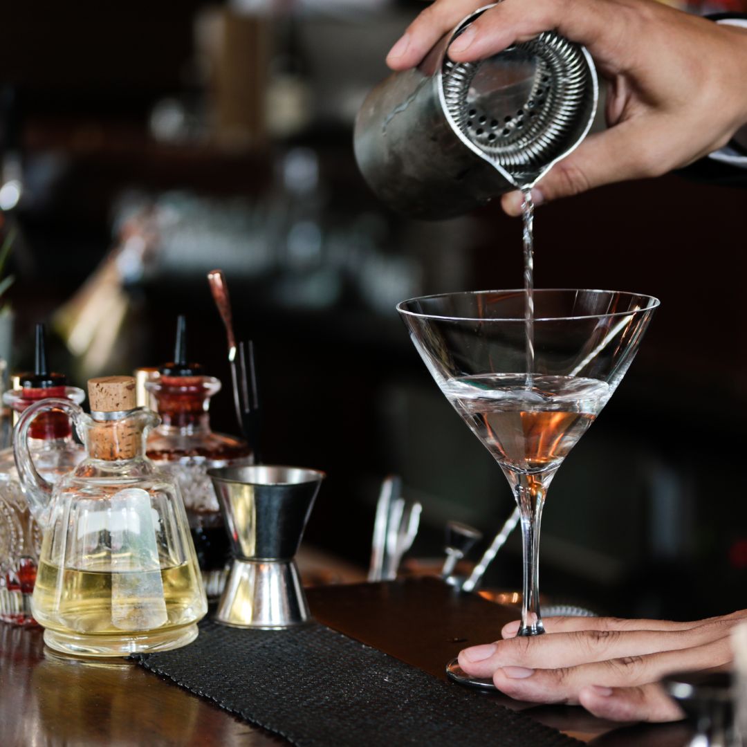 bartender pouring a beverage out of a strainer