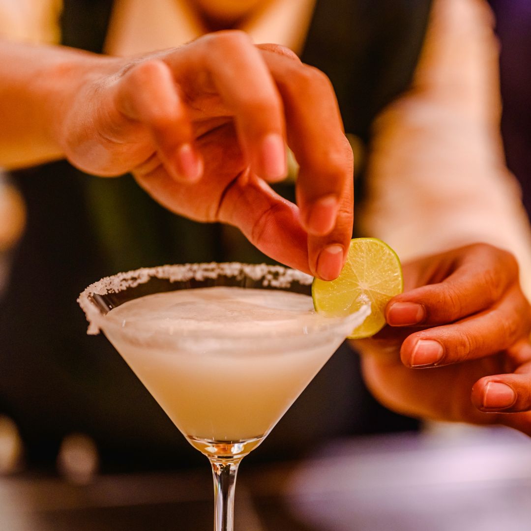 person putting a lime on the rim of a martini glass