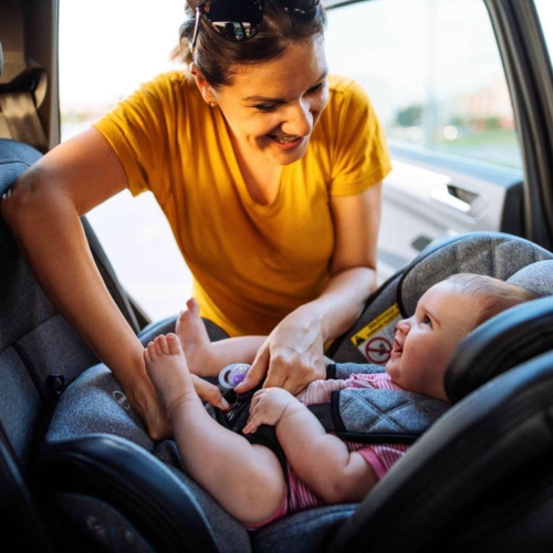 baby smiling at woman putting then in a car seat