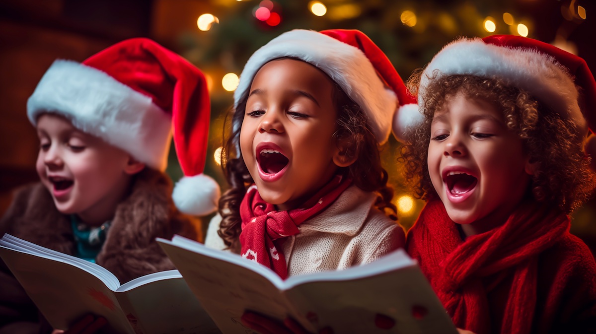 three children wearing santa hats, singing