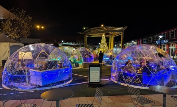 dining igloos put up outdoors by a pagoda and decorated christmas tree