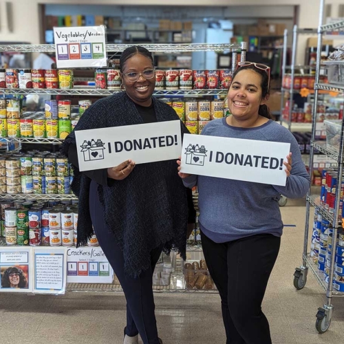 two people standing in front of racks of food holding 