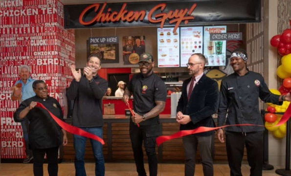 group of people cutting a red ribbon in front of Chicken Guy storefront