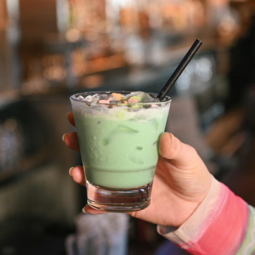 hand holding out a green beverage