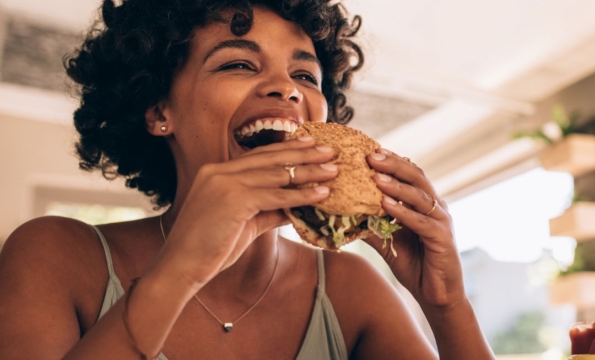 person laughing and holding a burger