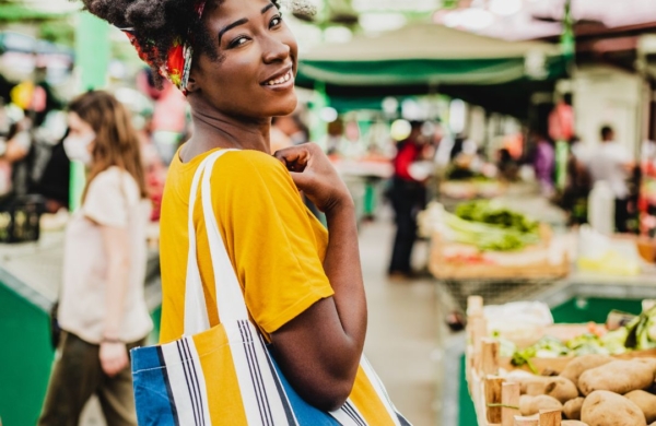 person holding a bag and smiling at an open air market