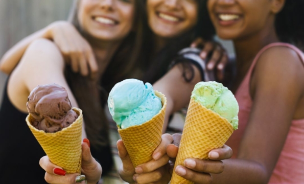 three young people holding ice cream cones and smiling