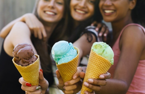 three young people holding ice cream cones and smiling