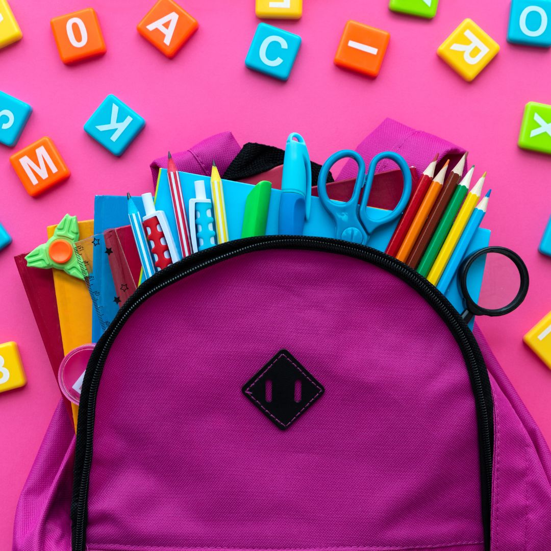pink back pack with school supplies hanging out of it