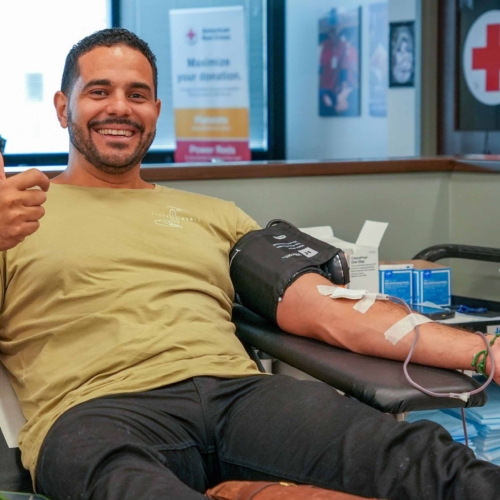 person sitting obn a reclining chair giving blood and giving a thumbs up