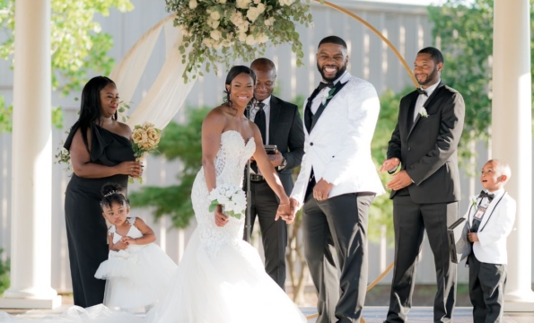 smiling couple in wedding attire at an outdoor alter