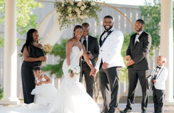 smiling couple in wedding attire at an outdoor alter