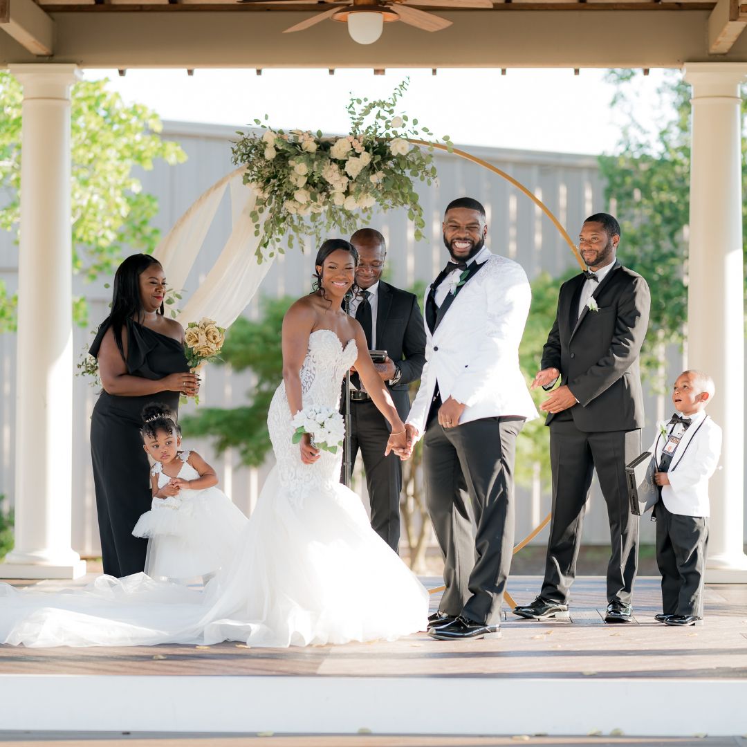 smiling couple in wedding attire at an outdoor alter