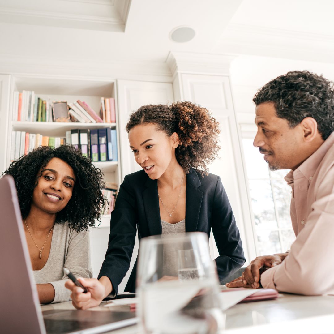 three people seated and looking at computer screen