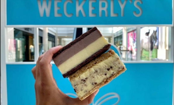 hand holding an ice cream sandwich in front of a Weckerlys sign