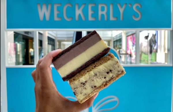 hand holding an ice cream sandwich in front of a Weckerlys sign