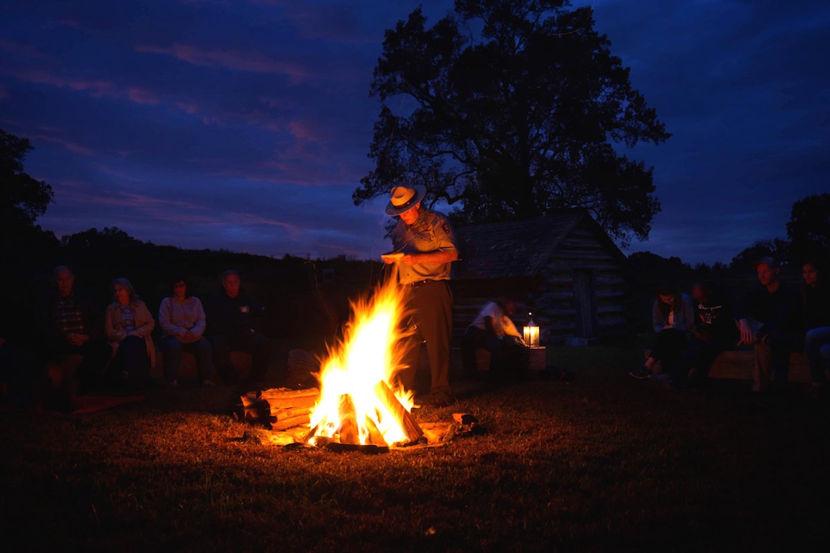 ranger standing by a camp fire